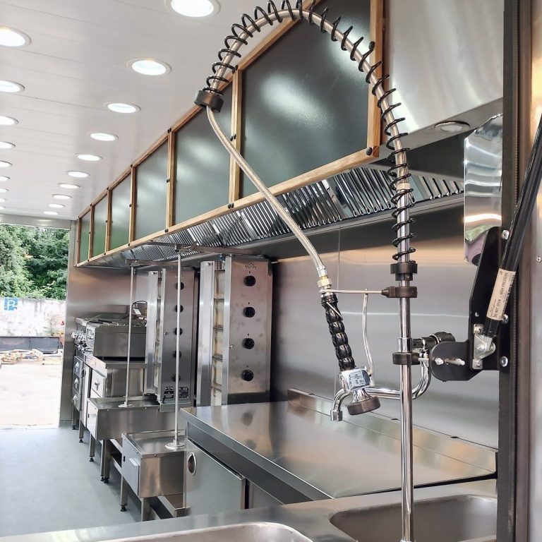 Foodtrailer-Innenausbau in Weiß – modern & hygienisch Innenraum eines Foodtrailers in Weiß mit Edelstahltechnik, Oberschränken, LED-Decke und Arbeitszeile – für Catering & Events